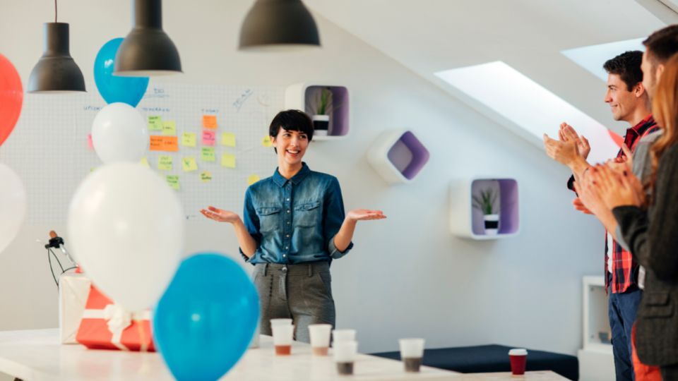 Woman being applauded for her good work in a festive work environment.